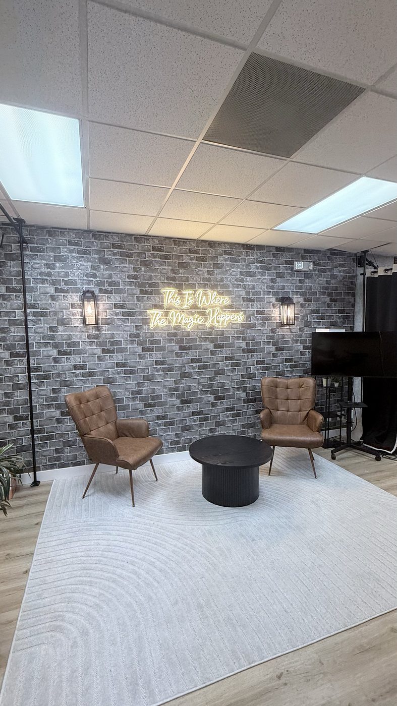 Lounge set with brick wall, neon sign and leather chairs